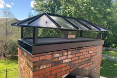 Custom Hip and Ridge Stainless Steel Multi-Flue Chimney Cap powdercoated black with Skirt installed on a brick chimney.