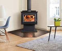 Wood stove in a room with a rug, chair, and table.