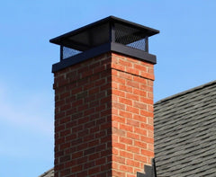 Brick chimney with a metal cap against a clear blue sky