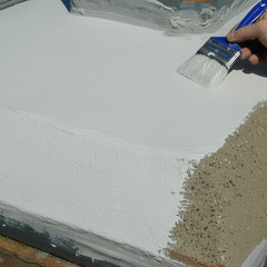 Person applying white chimney crown sealer to a surface using a blue brush.